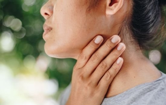 woman holding neck in discomfort - what to know about head and neck cancers