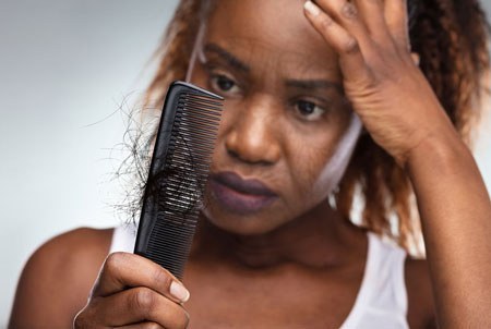 Cancer Treatment - Frustrated Black Female Losing Hair in a Comb